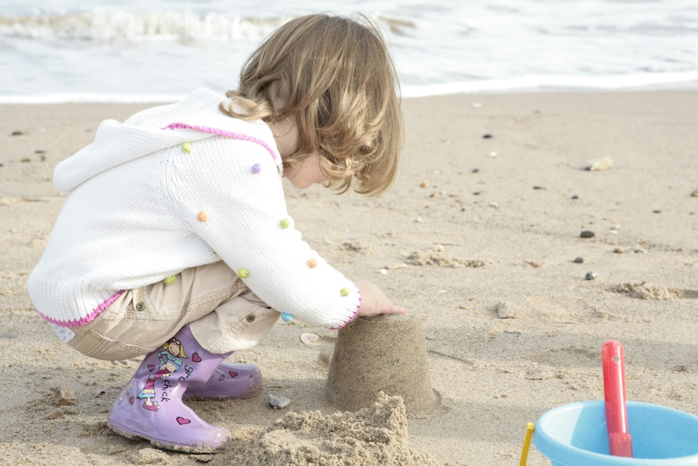 kid making sand castles on the beach